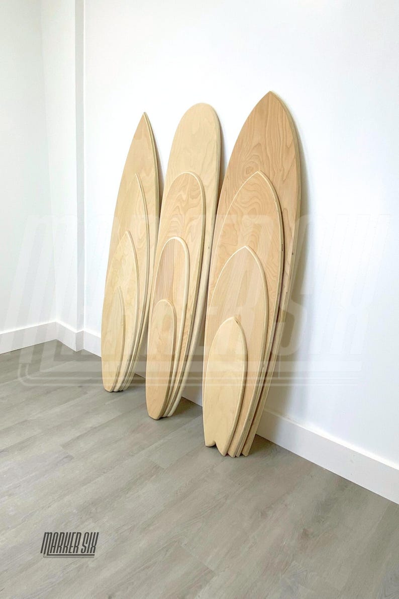 May include: Four wooden balance boards of varying sizes are stacked against a white wall. The boards are made of light wood and have a rounded shape. The boards are arranged in order of size, with the largest board at the bottom and the smallest board at the top. The boards are all leaning against the wall, and the bottom board is slightly tilted forward. The boards are all made of the same type of wood, and they have a smooth, polished finish. The boards are all in good condition, and they appear to be new. The boards are all in focus, and the background is blurred.