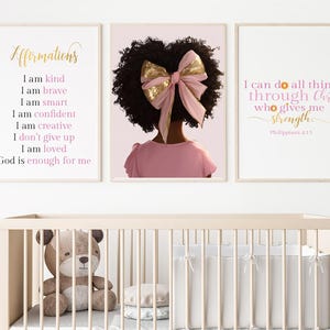 Puede incluir: Tres impresiones artísticas enmarcadas con citas inspiradoras y una cuna. Las impresiones presentan texto dorado y rosa sobre un fondo blanco. Una impresión dice "Afirmaciones" y enumera afirmaciones positivas. Otra muestra a una niña con un vestido rosa y un lazo. La tercera impresión dice "Puedo hacer todas las cosas a través de Cristo."