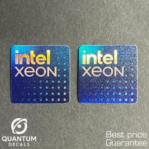 May include: Two square Intel Xeon stickers with a holographic blue background. The word "intel" is in yellow and the word "XEON" is in white. The stickers are on a dark gray surface. The text "QUANTUM DECALS" is below the stickers.