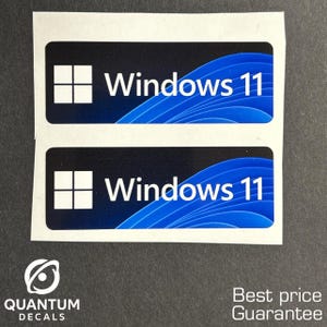 May include: Two rectangular stickers with the Windows 11 logo. Each sticker has a black background with a white Windows logo and the words "Windows 11" in white. The bottom left corner has the Quantum Decals logo.