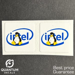 May include: Two white square stickers with the Intel logo in blue and a cartoon penguin. The penguin has a black body, white belly, and yellow feet. The stickers are on a gray surface. The text "QUANTUM DECALS" is at the bottom left.