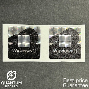 May include: Two holographic Windows 11 stickers with a black background and silver accents. The stickers have a square design with the Windows logo and the text "Windows 11". The stickers are on a white backing.