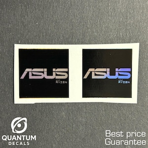 May include: Two black square stickers with the ASUS logo and "Ryzen" text in white and purple. The stickers are on a white background. The bottom left corner has a logo that says "QUANTUM DECALS".