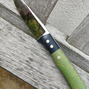 Peut inclure: Un couteau en acier inoxydable avec une lame polie et un manche avec une mitre noire et une poignée en bois vert. La poignée est fixée avec des rivets en laiton. Le couteau est conçu pour la cuisine ou l'extérieur.