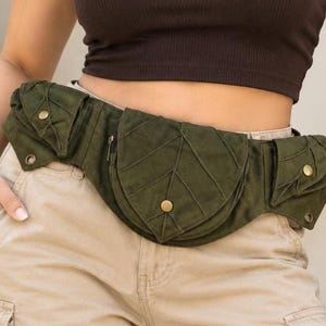 May include: An olive green waist bag featuring three distinct pockets with leaf-shaped flaps. Each pocket is secured with a small metallic snap button. The central pocket is larger and rounded, while the two side pockets are smaller and angular.