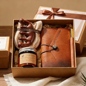 May include: A gift set in a brown box with a brown ribbon. The set includes a brown leather journal, a wooden pen, a wooden comb, and a small jar of scented candle. The journal has the text "COMMITTED TO EXCELLENCE".