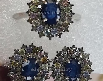 May include: A jewellery set comprising a ring and two earrings. Each piece features a central dark blue gemstone encircled by smaller, colourful stones. The ring and earrings have a silver-coloured metal setting. The text "elegant jewelry" is visible.