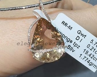 May include: A teardrop-shaped pendant with a large, light brown gemstone, surrounded by a halo of small, clear stones. The pendant hangs from a delicate silver chain. The tag reads "elegant-jewelry".