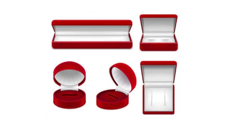 Pu&ograve; includere: Una collezione di scatole portagioie in velluto rosso di varie forme e dimensioni, inclusi design rettangolari e rotondi. Le scatole sono aperte e chiuse, rivelando interni bianchi, perfette per anelli e altri piccoli oggetti.