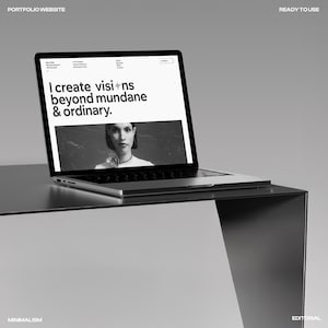 May include: A silver laptop displaying a website with the text "I create visions beyond mundane & ordinary." The laptop is on a minimalist black table. The words "PORTFOLIO WEBSITE" and "READY TO USE" are visible.