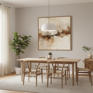 May include: A light wood dining table with four matching chairs featuring woven seats, positioned under a white dome pendant light. A large square abstract painting with beige, brown, and white tones hangs on the wall above the table.