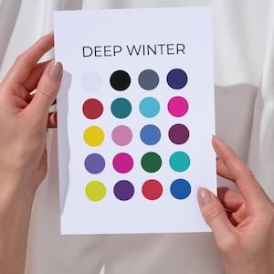 Può includere: Una carta bianca con la scritta "DEEP WINTER" e una griglia di punti colorati. I punti includono sfumature di bianco, nero, rosso, verde acqua, rosa e blu. La carta è tenuta da due mani.