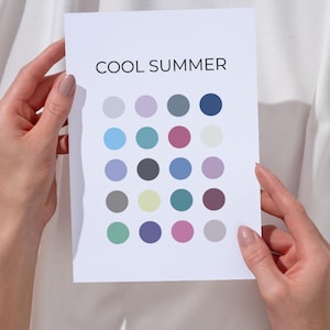 Puede incluir: Una tarjeta blanca sostenida por dos manos, con el texto "COOL SUMMER" sobre una cuadrícula de veintiún círculos de colores. Los círculos son en tonos de azul, morado, rosa, gris y verde.