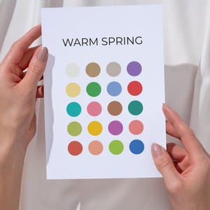 Może przedstawiać: Biała karta z napisem "WARM SPRING" i siatką kolorowych kół. Koła są w różnych odcieniach żółtego, zielonego, różowego, fioletowego i niebieskiego. Karta jest trzymana przez dwie ręce.