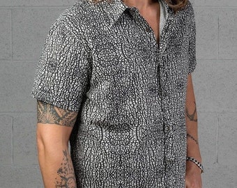 Peut inclure: Une chemise à manches courtes à boutons, noire et blanche, avec un motif texturé. La chemise a un col et une fermeture à boutons.