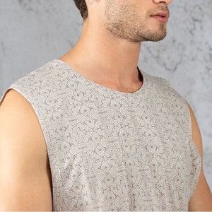 May include: A sleeveless shirt with a beige background and a repeating pattern of small, intricate black designs.