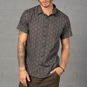 May include: A short-sleeved button-down shirt with a brown and black abstract print. The shirt has a collared neckline and a relaxed fit.
