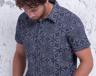 Può includere: Una camicia a maniche corte con bottoni, con sfondo blu scuro e motivo geometrico bianco.