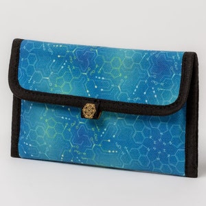 May include: A blue and green zippered wallet with a black trim and a gold mandala-shaped button. The wallet has a pattern of chemical structures on it.
