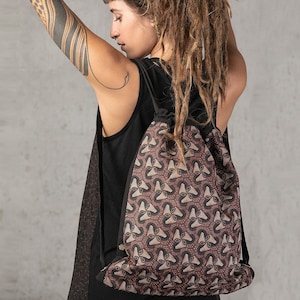 Könnte beinhalten: Ein brauner Rucksack mit Kordelzug und einem schwarzen geometrischen Muster. Der Rucksack ist aus weichem, strapazierfähigem Stoff gefertigt und hat einen Kordelzugverschluss.