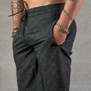 May include: Black swim trunks with a green and black geometric pattern. The trunks have a drawstring waist and a side pocket.