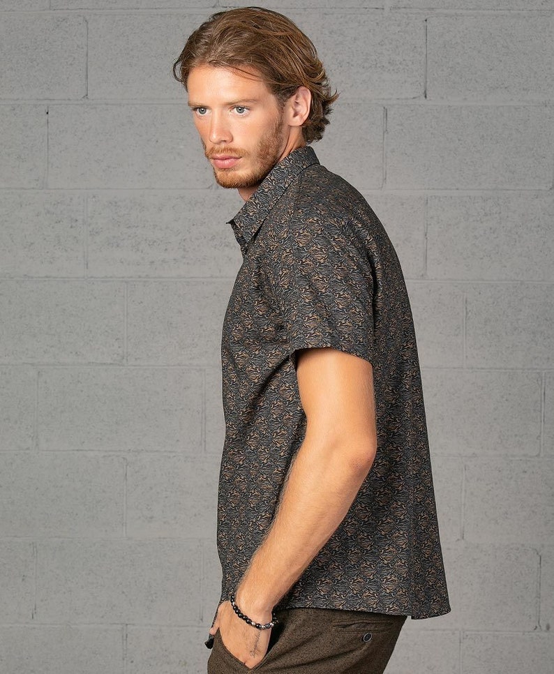 May include: A short-sleeved button-down shirt with a brown and black abstract print. The shirt has a collared neckline and a relaxed fit.