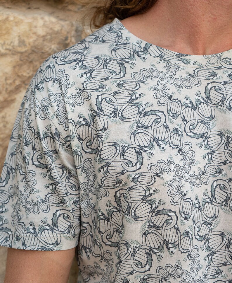 May include: A short-sleeved shirt with a white background and a black and green pattern. The pattern is a repeating design of interlocking circles and lines.