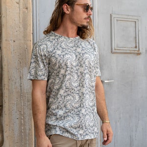 May include: A white t-shirt with a black and white patterned design. The shirt has a crew neck and short sleeves.