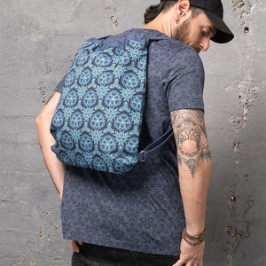 Puede incluir: Una mochila azul de cord&oacute;n con un patr&oacute;n geom&eacute;trico. La mochila la lleva puesta una persona con un tatuaje en el brazo.