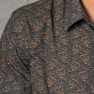May include: A short-sleeved shirt with a brown and black abstract pattern. The pattern resembles a tiger stripe.