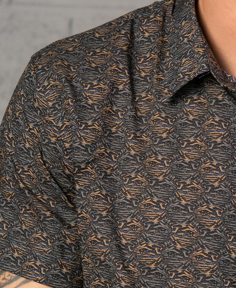 May include: A short-sleeved shirt with a brown and black abstract pattern. The pattern resembles a tiger stripe.