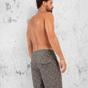 May include: A pair of dark brown swim trunks with a paisley pattern. The trunks have a drawstring waist and a back pocket.