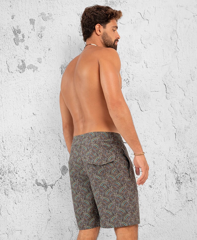 May include: A pair of dark brown swim trunks with a paisley pattern. The trunks have a drawstring waist and a back pocket.