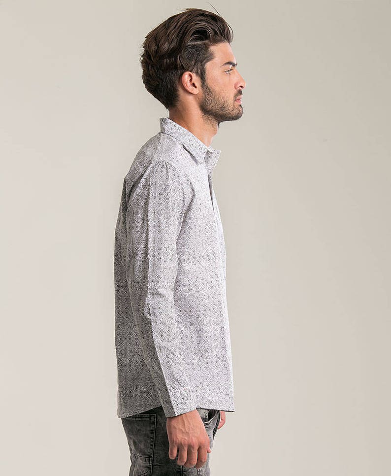 May include: A white long-sleeved button-down shirt with a black and white geometric pattern.