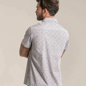 May include: A white short-sleeved button-down shirt with a black geometric pattern.