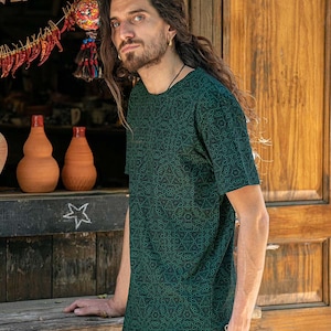 May include: A dark green t-shirt with a geometric pattern. The shirt has a crew neck and short sleeves.