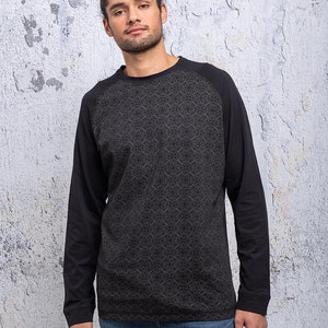 May include: A black long-sleeve shirt with a patterned design on the front and black sleeves. The shirt has a crew neck.