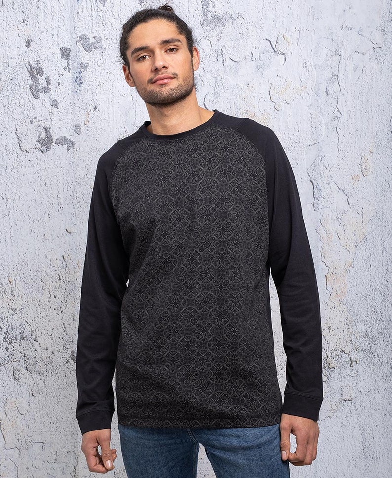 May include: A black long-sleeve shirt with a patterned design on the front and black sleeves. The shirt has a crew neck.