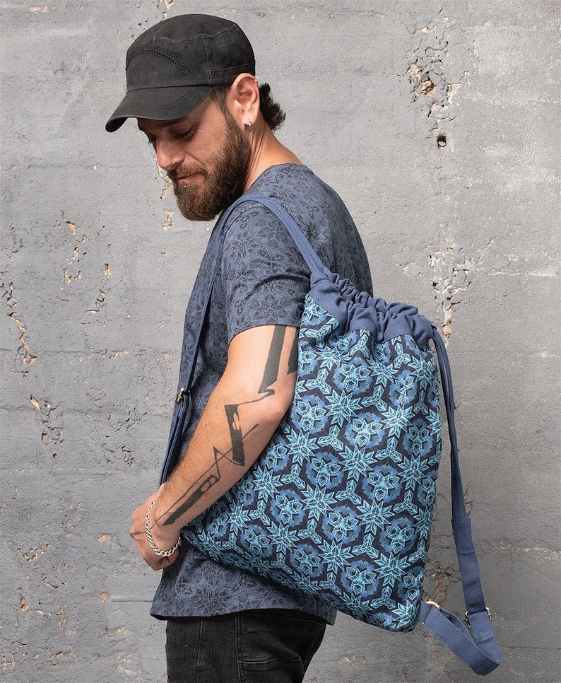 Puede incluir: Una mochila azul de cord&oacute;n con un patr&oacute;n geom&eacute;trico. La mochila tiene correas ajustables y un cierre de cord&oacute;n.