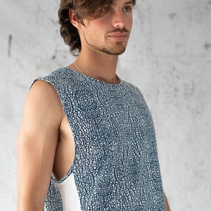 Puede incluir: Una camiseta sin mangas con fondo blanco y un patr&oacute;n abstracto azul. La camiseta tiene una franja blanca en el lateral.