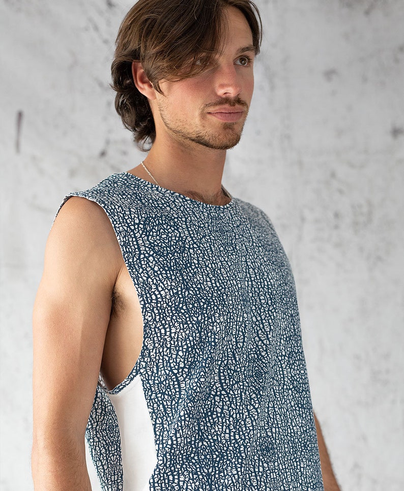 Puede incluir: Una camiseta sin mangas con fondo blanco y un patr&oacute;n abstracto azul. La camiseta tiene una franja blanca en el lateral.