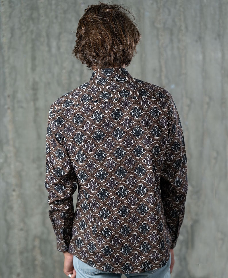 May include: A long-sleeved button-down shirt with a brown, white, and purple geometric pattern. The shirt is made of a lightweight fabric and has a classic collar and buttoned cuffs. The shirt is shown from the back.