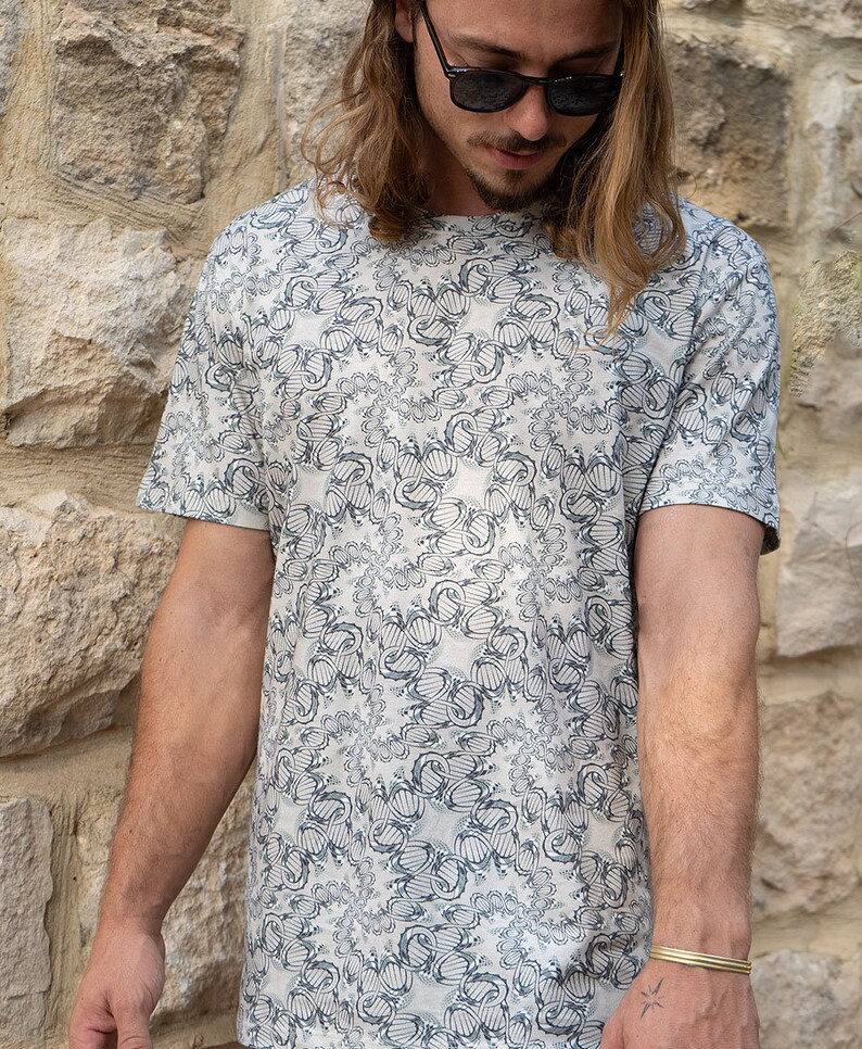 May include: A white t-shirt with a black and gray abstract pattern. The pattern is a repeating design of swirls and circles.