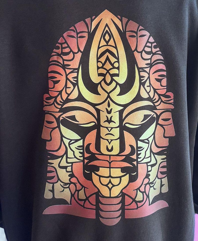 May include: Dark gray sweatshirt featuring a vibrant, stylized graphic of a face composed of multiple faces. The design uses a gradient of orange, yellow, and red hues. The graphic is centered on the front of the shirt.
