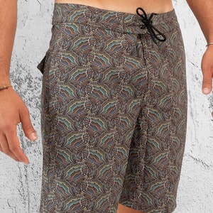 May include: Brown swim trunks with a paisley pattern. The trunks have a drawstring waist and a side pocket.
