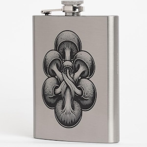 May include: A stainless steel hip flask featuring a black and white mushroom design. The flask has a hinged cap and a small, attached metal cap. The design shows several interconnected mushrooms.