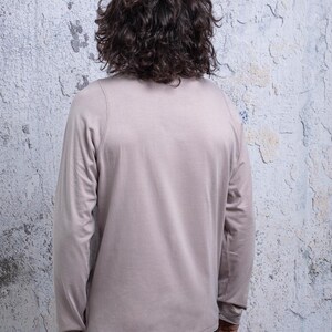 May include: A long-sleeved shirt in a light gray color. The shirt has a crew neck and a relaxed fit.