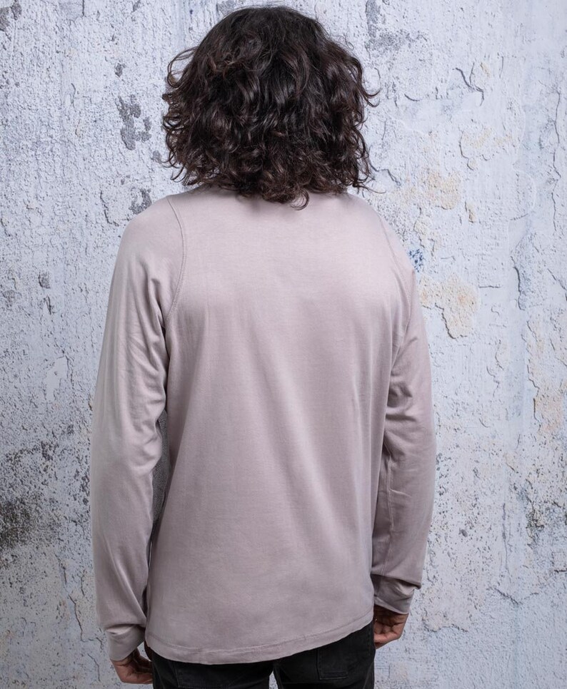 May include: A long-sleeved shirt in a light gray color. The shirt has a crew neck and a relaxed fit.