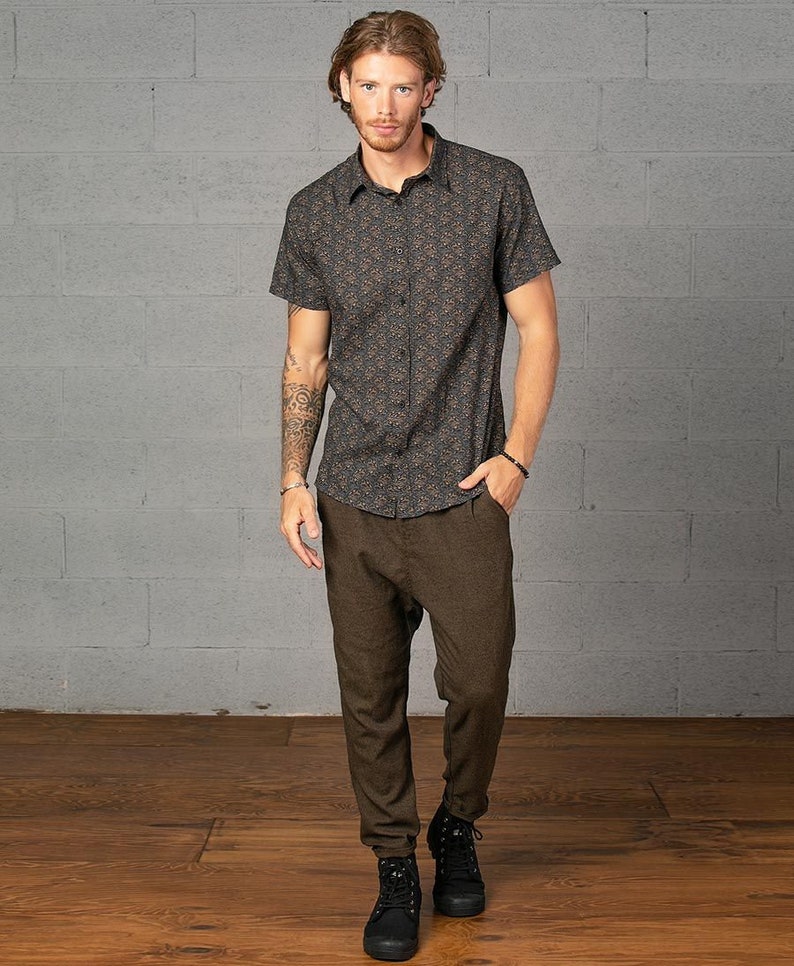 May include: A man is wearing a dark blue short-sleeved shirt with a brown floral pattern. He is also wearing brown pants and black shoes.