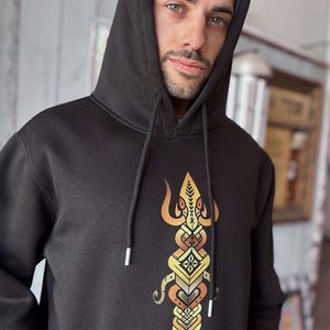 May include: Black hooded sweatshirt with a detailed, colorful graphic on the front. The graphic features a symmetrical design with orange, yellow, and brown elements. The hoodie has a drawstring and a hood.